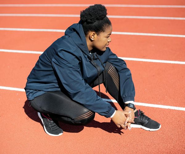 Runner stretching on a track, focused and determined.